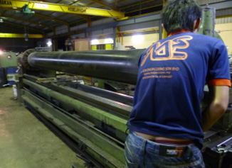 Technician machining a long roller on the Klang workshop lathe